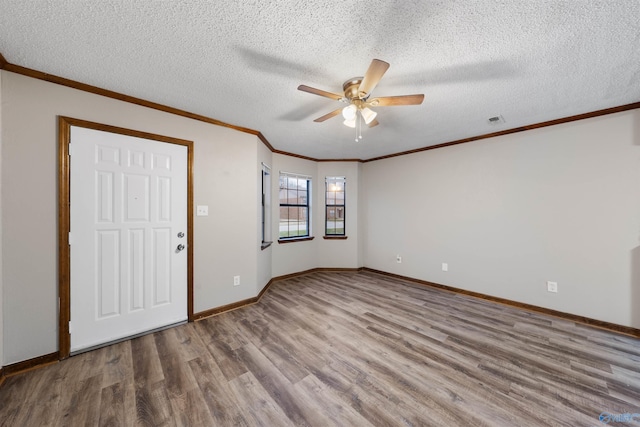 empty room featuring visible vents, ceiling fan, wood finished floors, and ornamental molding