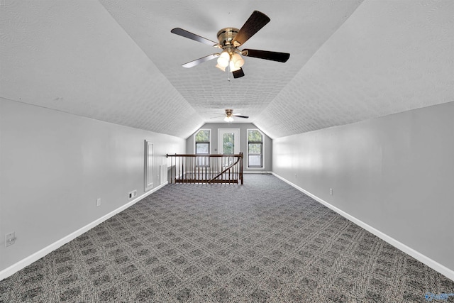 additional living space with ceiling fan, vaulted ceiling, carpet, and a textured ceiling