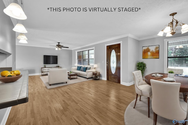 interior space with light wood-type flooring, ceiling fan with notable chandelier, and ornamental molding