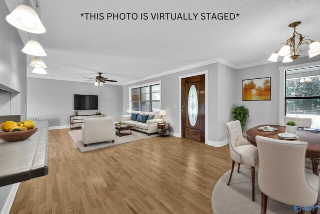 spare room with light wood-type flooring, a textured ceiling, an inviting chandelier, and crown molding