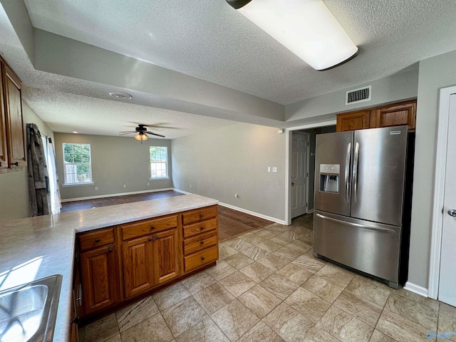 kitchen featuring ceiling fan, sink, a textured ceiling, and stainless steel refrigerator with ice dispenser