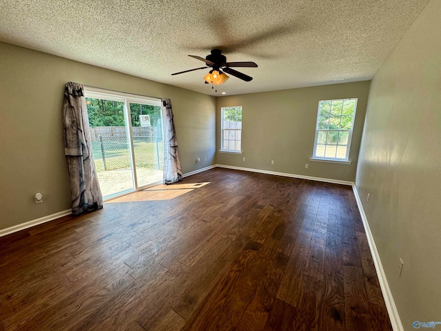 unfurnished room with a textured ceiling, a healthy amount of sunlight, ceiling fan, and dark wood-type flooring