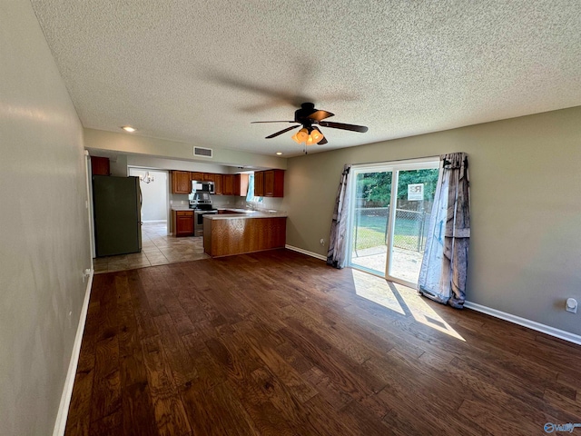 unfurnished living room with hardwood / wood-style floors, ceiling fan, and a textured ceiling