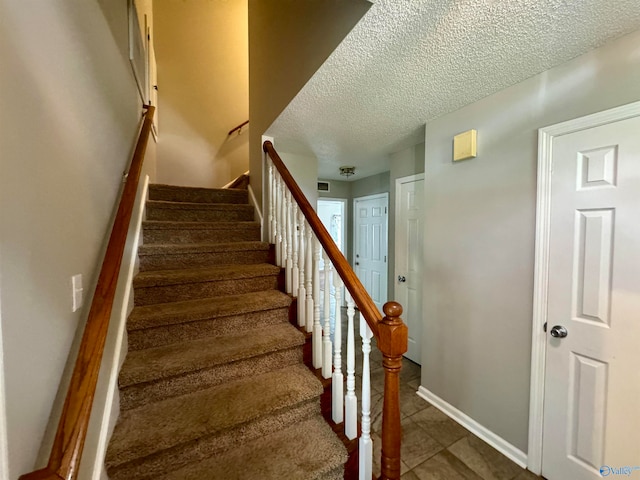 staircase featuring a textured ceiling and tile patterned flooring