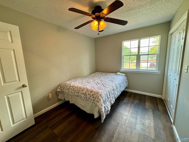 bedroom featuring a textured ceiling, dark hardwood / wood-style flooring, ceiling fan, and a closet