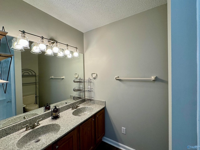 bathroom with vanity, toilet, and a textured ceiling