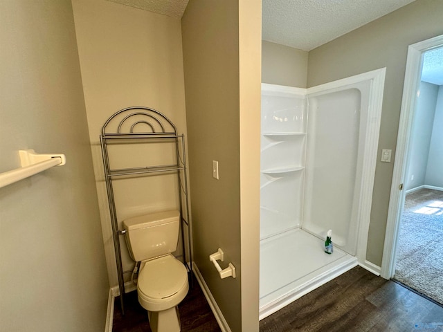 bathroom featuring toilet, hardwood / wood-style flooring, walk in shower, and a textured ceiling