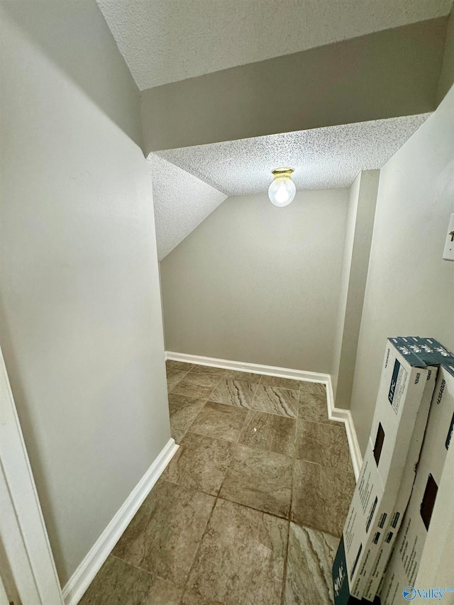 corridor featuring lofted ceiling and a textured ceiling