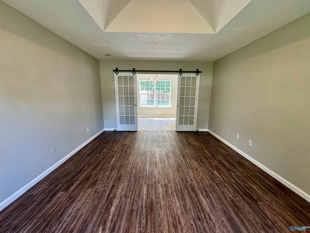 spare room featuring a textured ceiling, a barn door, and dark hardwood / wood-style floors