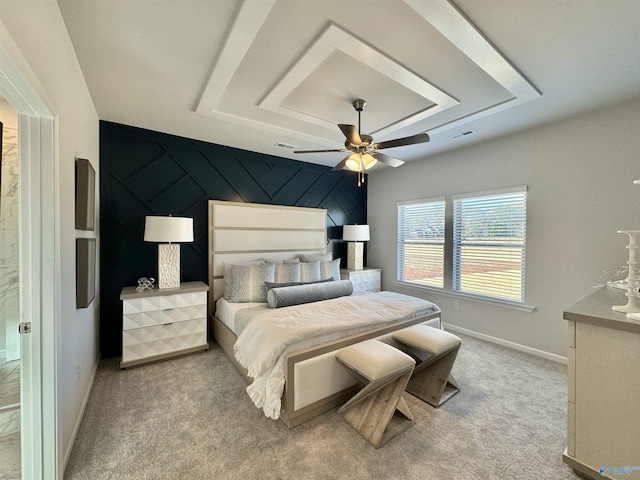 carpeted bedroom featuring a tray ceiling, baseboards, visible vents, and ceiling fan