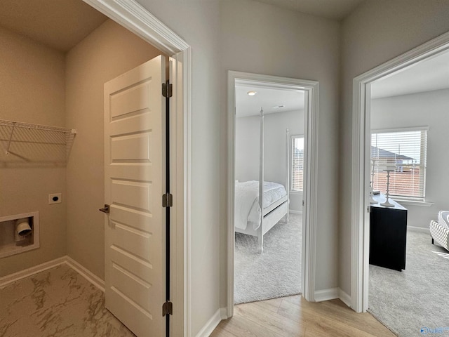 laundry room featuring baseboards, hookup for an electric dryer, light carpet, and light wood finished floors