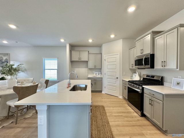 kitchen featuring light wood-type flooring, recessed lighting, gray cabinets, appliances with stainless steel finishes, and a sink