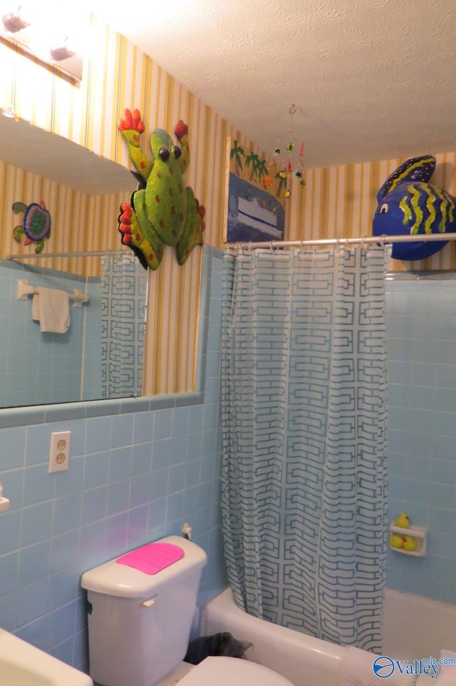 bathroom featuring tile walls, shower / bath combination with curtain, a textured ceiling, and toilet