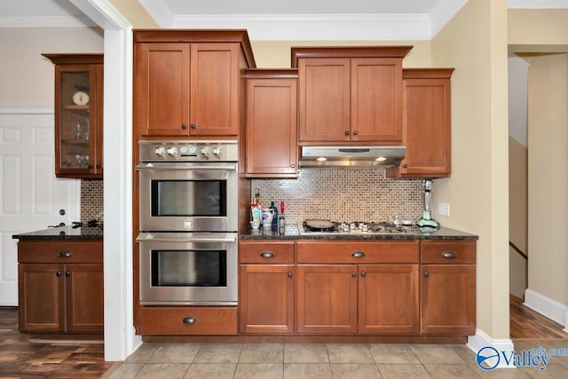 kitchen featuring ornamental molding, appliances with stainless steel finishes, and dark stone counters