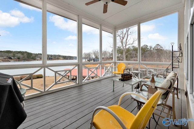 sunroom with ceiling fan and a water view