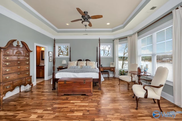 bedroom featuring crown molding, a tray ceiling, and wood-type flooring