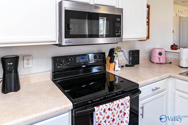 kitchen featuring black electric range oven and white cabinetry