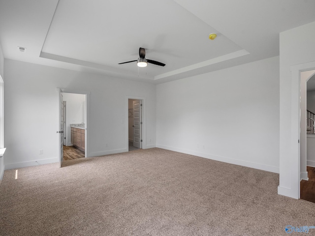 unfurnished bedroom with a raised ceiling, light carpet, and ceiling fan