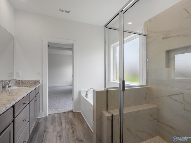 bathroom with vanity, shower with separate bathtub, and hardwood / wood-style floors