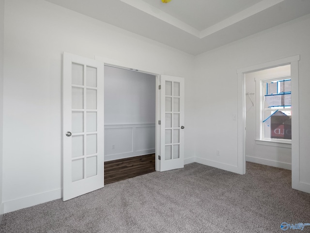 unfurnished bedroom with french doors, dark colored carpet, and a closet