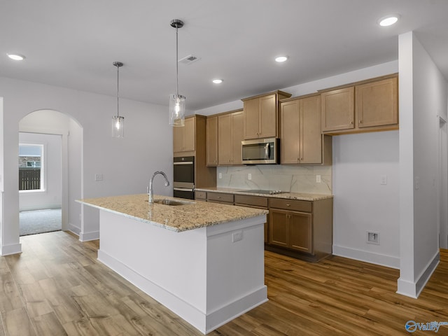 kitchen with appliances with stainless steel finishes, pendant lighting, a center island with sink, and hardwood / wood-style floors