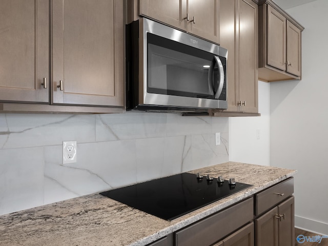 kitchen with light stone counters, tasteful backsplash, black electric cooktop, and hardwood / wood-style floors