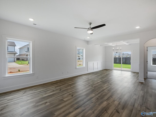 unfurnished living room featuring dark hardwood / wood-style flooring, ceiling fan with notable chandelier, and plenty of natural light