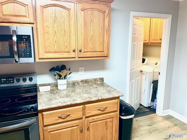 kitchen featuring light hardwood / wood-style floors, light stone countertops, appliances with stainless steel finishes, and independent washer and dryer