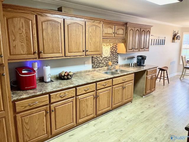 kitchen featuring sink, backsplash, light hardwood / wood-style flooring, and ornamental molding