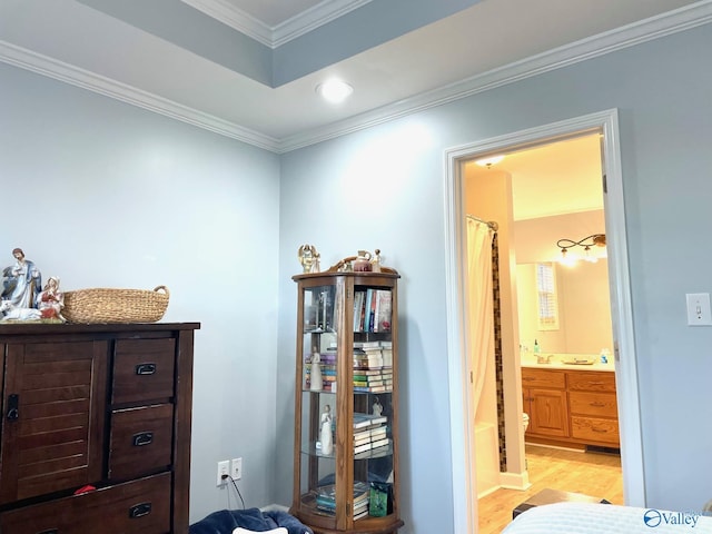 bedroom featuring crown molding, light hardwood / wood-style floors, and ensuite bath