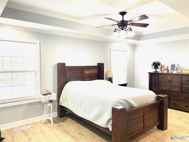 bedroom featuring ceiling fan, a tray ceiling, light hardwood / wood-style flooring, and ornamental molding