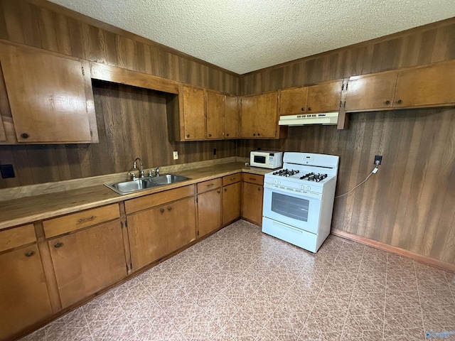 4435 Pilgrims Rest Rd, Southside, AL 35907 - kitchen featuring white appliances, under cabinet range hood, wooden walls, a textured ceiling, and brown cabinetry