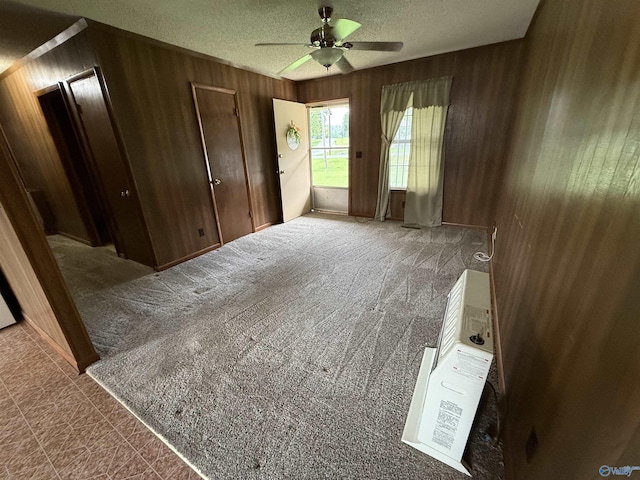 4435 Pilgrims Rest Rd, Southside, AL 35907 - empty room featuring wooden walls, a ceiling fan, a textured ceiling, and carpet