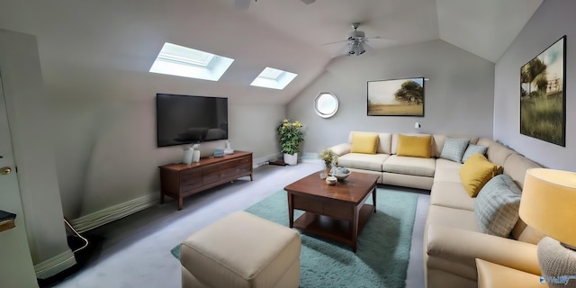 carpeted living room with ceiling fan and vaulted ceiling with skylight