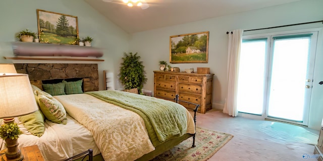 bedroom featuring a stone fireplace, vaulted ceiling, and access to outside