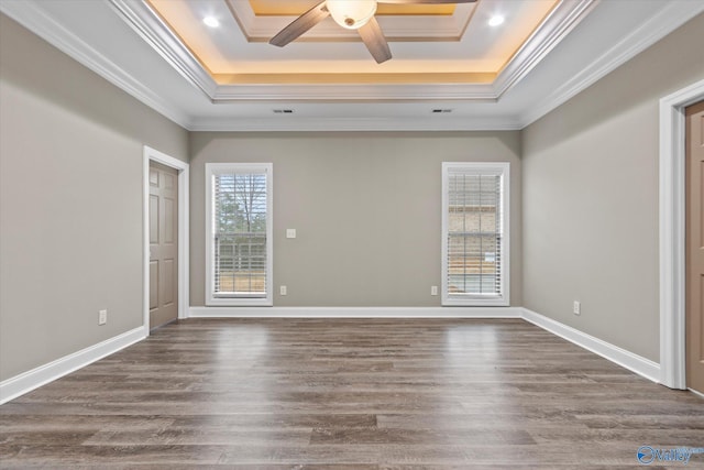 spare room with crown molding, dark hardwood / wood-style floors, a tray ceiling, and ceiling fan