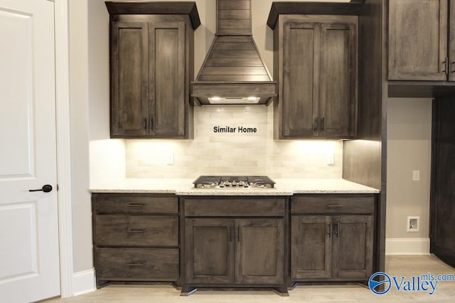 BELLEWOOD-B Mallard Dr, Madison, AL 35756 - kitchen with premium range hood, stainless steel gas stovetop, tasteful backsplash, dark brown cabinetry, and light stone countertops