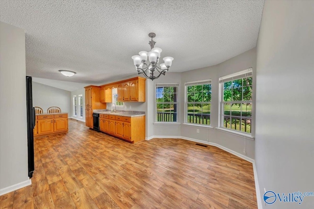 kitchen featuring visible vents, an inviting chandelier, a sink, light countertops, and light wood-type flooring