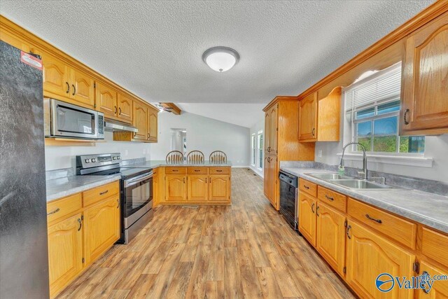 kitchen with a sink, a peninsula, under cabinet range hood, black appliances, and light wood-style flooring