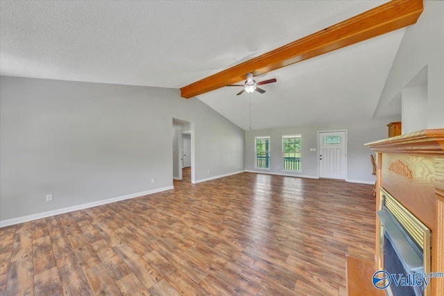 unfurnished living room with a ceiling fan, a textured ceiling, a fireplace, wood finished floors, and vaulted ceiling with beams