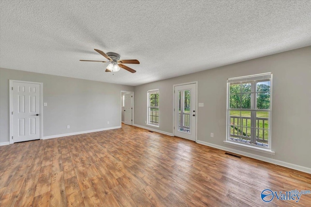unfurnished living room with visible vents, baseboards, wood finished floors, and ceiling fan