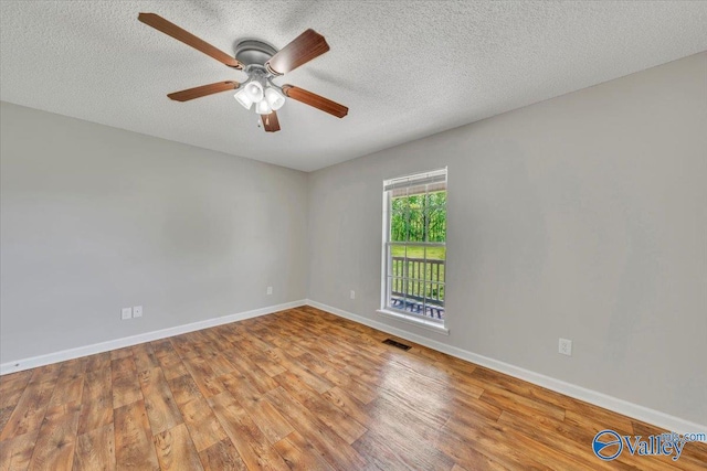 unfurnished room featuring visible vents, baseboards, ceiling fan, a textured ceiling, and wood finished floors