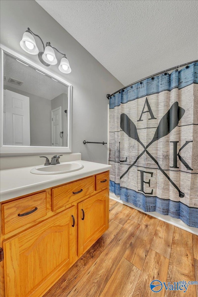 bathroom featuring visible vents, vanity, wood finished floors, and a textured ceiling