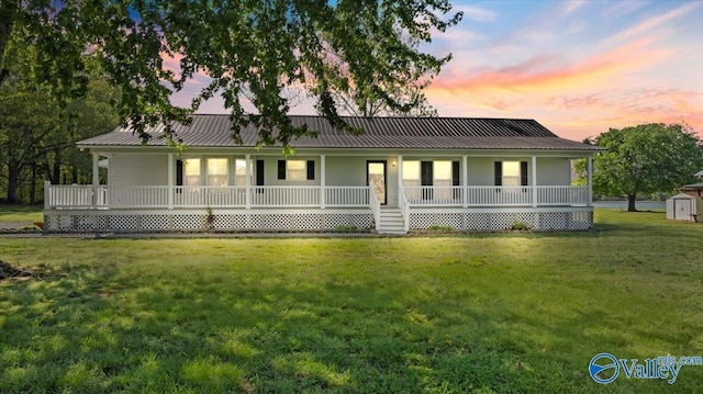 farmhouse-style home with an outbuilding, a shed, covered porch, metal roof, and a front lawn
