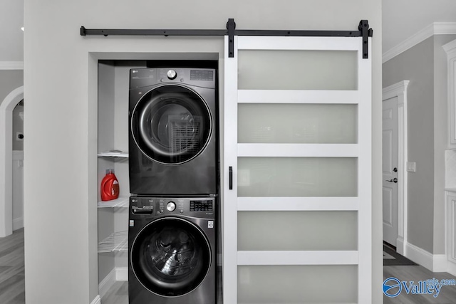 washroom featuring hardwood / wood-style floors, stacked washer and clothes dryer, and ornamental molding