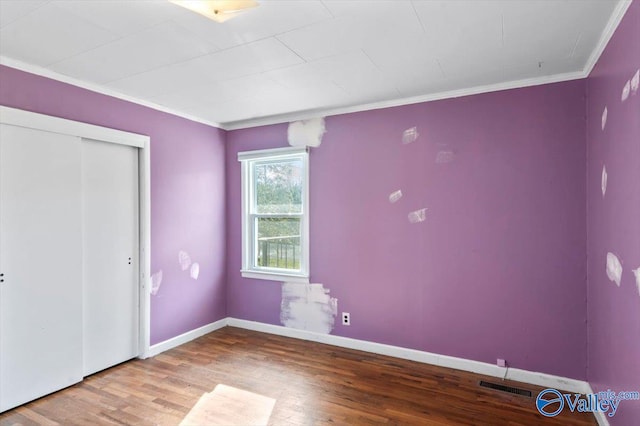 unfurnished bedroom with hardwood / wood-style flooring, a closet, and ornamental molding