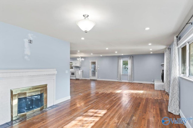 unfurnished living room featuring a fireplace, hardwood / wood-style flooring, and a notable chandelier