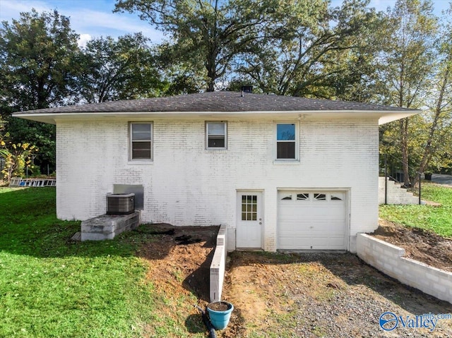 exterior space with central air condition unit, a garage, and a lawn