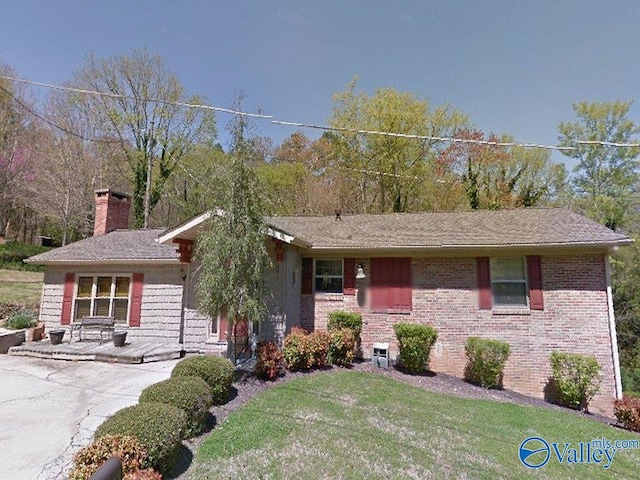 ranch-style home with a front yard, a patio area, brick siding, and a chimney