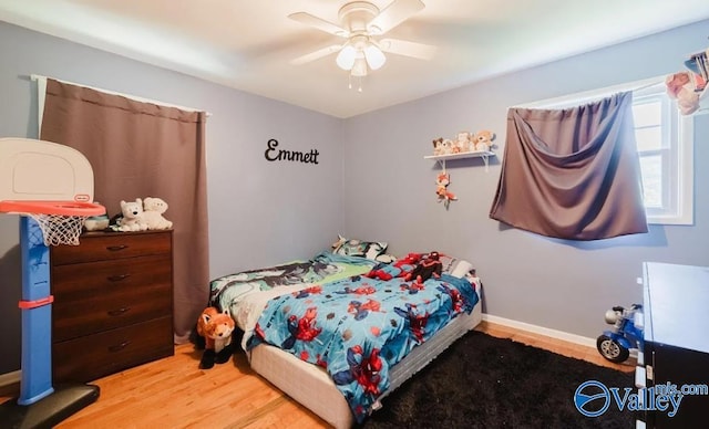 bedroom with baseboards, a ceiling fan, and light wood-style floors